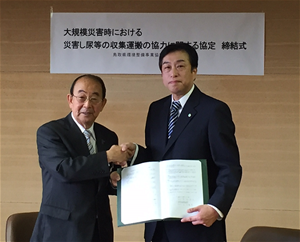 協定締結式の写真。米子市長と鳥取県環境整備事業共同組合の代表者が握手しています。