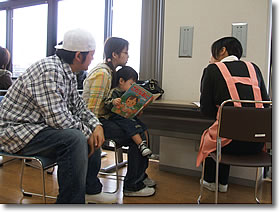 子どもを抱えたお母さんとお父さんが、保健師と話をしています。